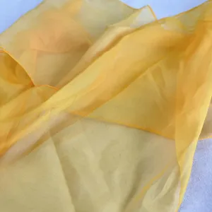 Gros plan sur le tissu léger et transparent du foulard jaune avec des coutures fines.