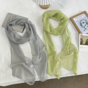 Vue détaillée de foulards légers en mousseline unie dans des tons de gris et de vert clair.