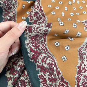 Close-up view of vintage green floral silk scarf, highlighting smooth texture and paisley border.