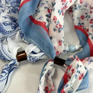 Dettaglio della sciarpa floreale azzurra con trama fine e anello di perle regolabile.