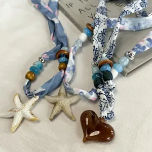 Exquisite silk scarf necklace with starfish and heart pendants, stylish summer accessory detail.