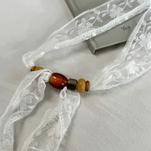 White lace ribbon necklace with beads, elegant streamer choker accessory for spring and summer.