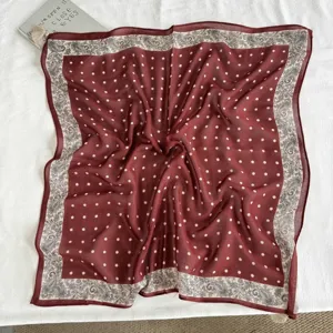 Detail view of maroon square scarf with white polka dots and vintage paisley border design.