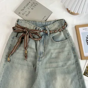Retro vintage light blue denim jeans with stylish brown striped beaded ribbon belt accessory.
