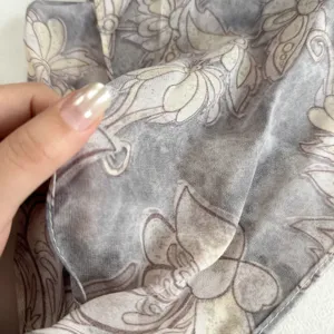 Close-up detail of grey floral silk neck scarf fabric texture elegant versatile accessory