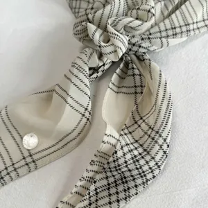 Chic black and white plaid ribbon scarf with elegant knot design and delicate button detail.