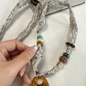 Gedetailleerd overzicht van vintage paisley zijden sjaal ketting met kleurrijke kralen en hanger.