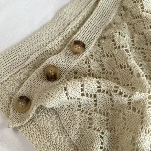 Detailgezicht van een cremekleurige gebreide rokverlenging met mooie schildpadknopen.
