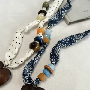 Detail van vintage sjaal ketting met kleurrijke kralen en houten hart hanger accessoire.