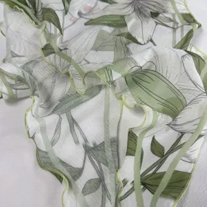 Gedetailleerde close-up van lichte bloemenprint hoofddoek met groene blaadranddetails.