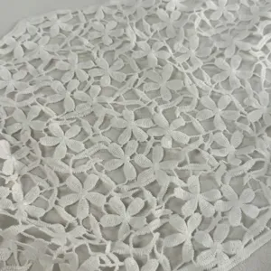 Weißes Blumen-Ausschnitt-Strick-Spitzengewebe Detail mit exquisiter Textur für modisches Design.