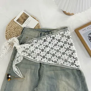 Detailansicht des weißen floralen Strickspitzentuchs und des Lagenrock-Outfits aus Jeans.