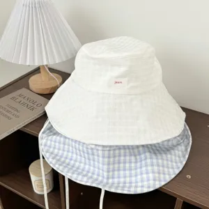 Chic checkered bucket hat with sun-shading wide brim and strings, displayed in cozy room.