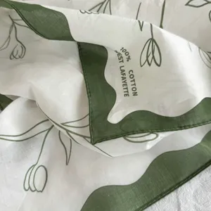 Detailed view of premium cotton square scarf with elegant green floral print and wavy edge.