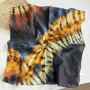 Dettaglio foulard quadrato in cotone tie dye, mostra un motivo artistico nero e giallo.
