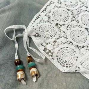 Detailed shot of white lace skirt extender with beaded tie design, stylish layering piece.