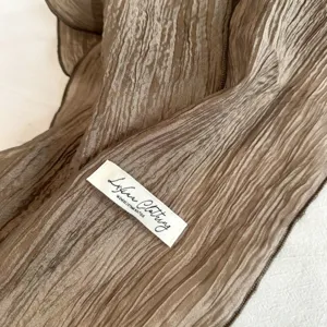 Close-up detail shot of a chic crinkled narrow scarf showing its soft lustrous textured fabric.