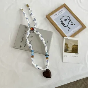 Detail shot of fabric necklace with blue print, wooden heart pendant and colorful beads.
