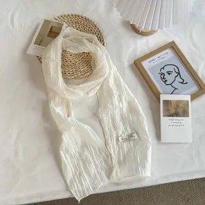Detail view of a white thin mesh scarf with wrinkled texture, elegant narrow design for women.