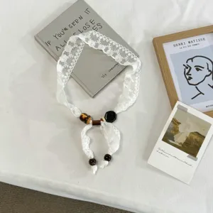 White lace ribbon necklace detail, featuring vintage beaded accents and delicate lace trim.