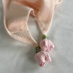Pink knitted triangular scarf detail with cute plaid tulip pendants and delicate green beads.