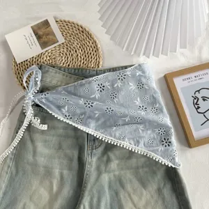 Blauwe geborduurde wikkelrok met witte kantafwerking detail in esthetische flat-lay.
