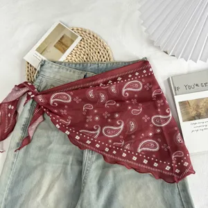 Detailed shot of dark red paisley triangular scarf styled on denim with aesthetic lifestyle props.