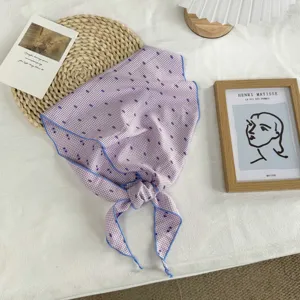 Nahaufnahme Detail eines lila gepunkteten Dreiecks-Seidentuchs mit blauem Saum fur Damen.