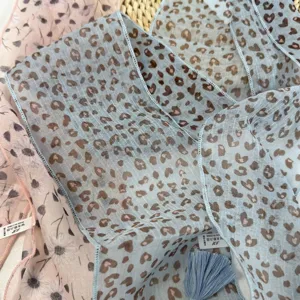 Vue détaillée d'un foulard léger pour femme avec pompons chics et imprimé floral délicat.