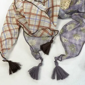 Vue détaillée du foulard léger à motifs floraux et pompons, accessoire d'été chic et élégant.
