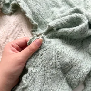 Vue rapprochée du foulard triangulaire tricoté montrant les volants délicats et la texture.
