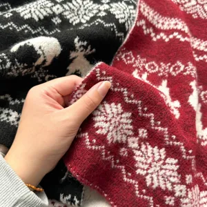 Close-up of winter thick knitted scarf featuring cozy reindeer and snowflake patterns.