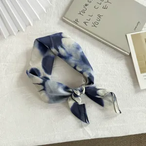 Primo piano dettagliato di un piccolo fazzoletto quadrato in cotone tie-dye blu e bianco.
