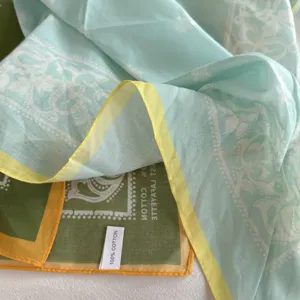 Gedetailleerde close-up van een 100% katoenen paisley bandana sjaal met contrastranden.