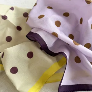 Gros plan détail d'un foulard en coton doux à pois, mettant en valeur la texture du tissu.