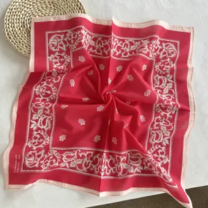 Gedetailleerd close-up van rode katoenen paisley bandana sjaal met fijne witte bloemmotieven.