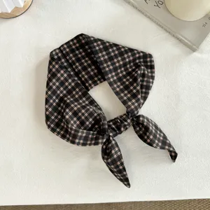 Primo piano dettagliato di una fascia per capelli in cotone a quadri neri e marroni.