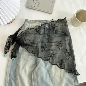 Jeans gecombineerd met zwarte kanten asymmetrische wikkelrok, stijlvol gelaagd detail.