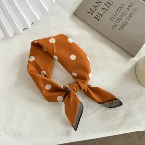 Détail de petit foulard carré à pois orange, tissu doux, accessoire de cou chic et élégant.