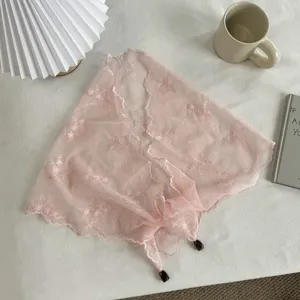 Detail van een roze kanten driehoekige sjaal met fijn bloemenborduurwerk en hangers.