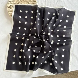 Gros plan sur les détails du foulard carré en coton noir et blanc à pois, montrant la texture.