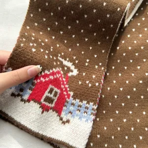 Primer plano detallado de bufanda de invierno tejida marrón con bonito patrón de cabaña nevada.
