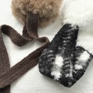 Nahaufnahme von flauschigen Plüsch-Ohrwärmern aus warmem Lammfell mit gemütlichen Strickbändern.
