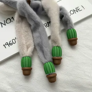 Primer plano detalle de bufanda de felpa con colgantes de cactus en maceta, suave.