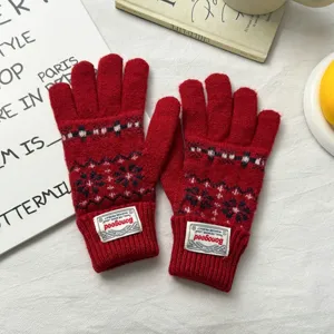 Close-up of red Fair Isle knit gloves with cozy wool texture and custom cuff label detail.