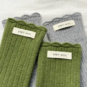 Detalle de guantes de invierno de lana tejida lisa, diseño sin dedos cálido con borde ondulado.