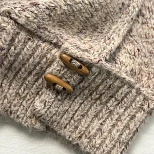 Close-up detail of knitted alpaca blend balaclava hoodie with wooden toggle buttons.