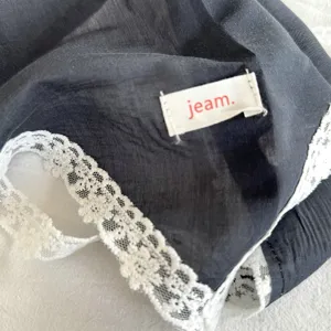 Detail van zwarte kanten driehoekige sjaal met fijne witte kanten rand en klein stoffen label.