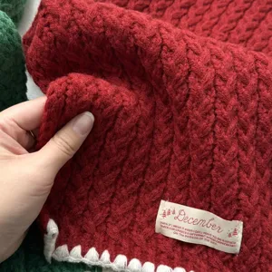 Gros plan détaillé d'un écharpe d'hiver en tricot torsadé rouge avec étiquette. Accessoire chaud.