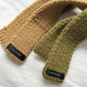 Knitted long narrow scarf close-up, cozy autumn winter warm neckwear in camel and olive green.